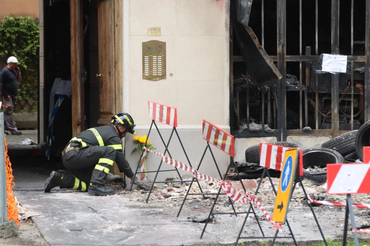 Un vigile del fuoco depone un fiore portato da un cittadino per commemorare le tre vittime dell'incendio in via Fra Galgario
