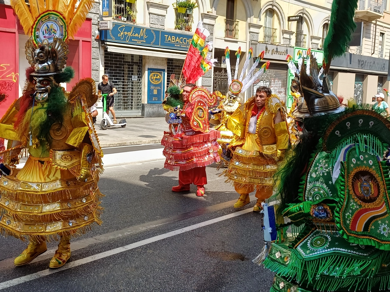 Uomini con maschere etniche della Bolivia nel festoso corteo a Milano