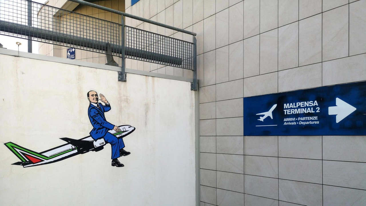 L’ex premier a cavallo della fusoliera di un aereo. È il nuovo murale che ritrae Silvio Berlusconi a opera... L’ex premier a cavallo della fusoliera di un aereo. È il nuovo murale che ritrae Silvio Berlusconi a opera...