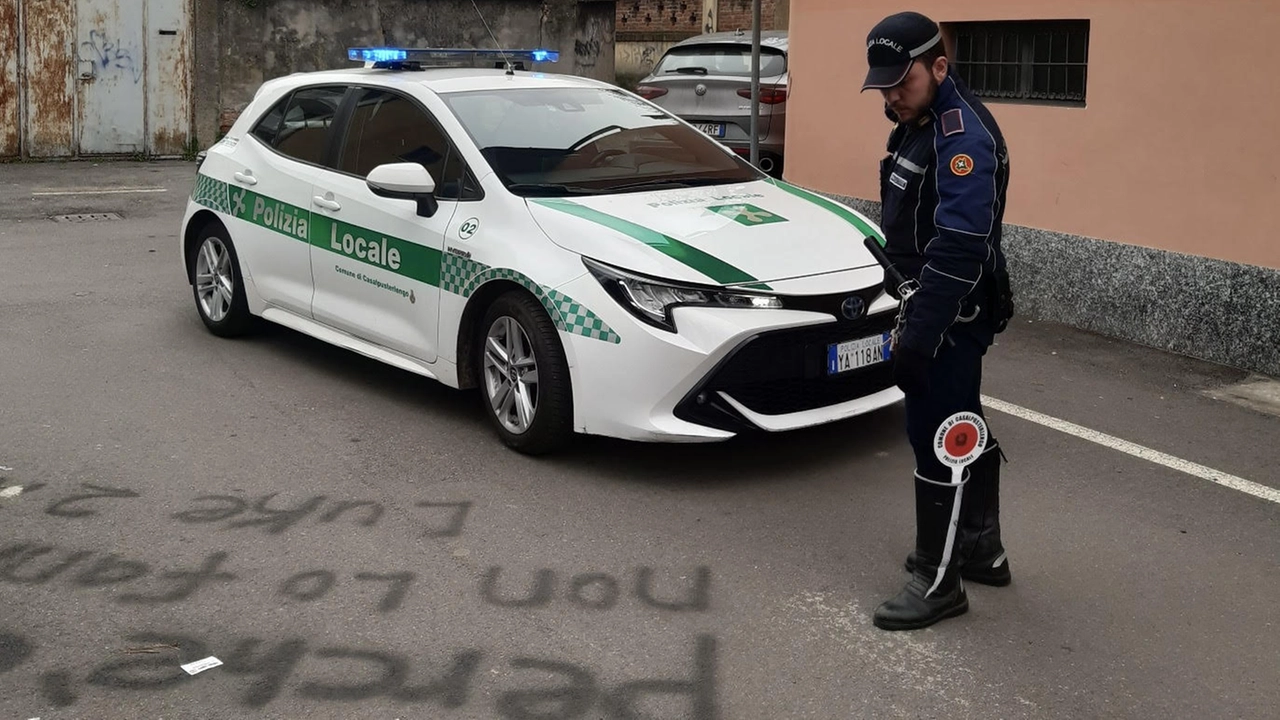 Un agente della polizia locale di Casalpusterlengo osserva una delle scritte tracciate sull'asfalto e su un muro della chiesa Un agente della polizia locale di Casalpusterlengo osserva una delle scritte tracciate sull'asfalto e su un muro della chiesa