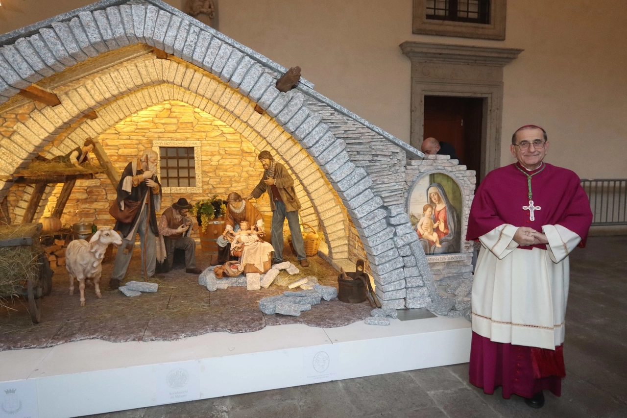 L'arcivescovo di Mario Delpini sorridente a fianco del presepe inaugurato oggi