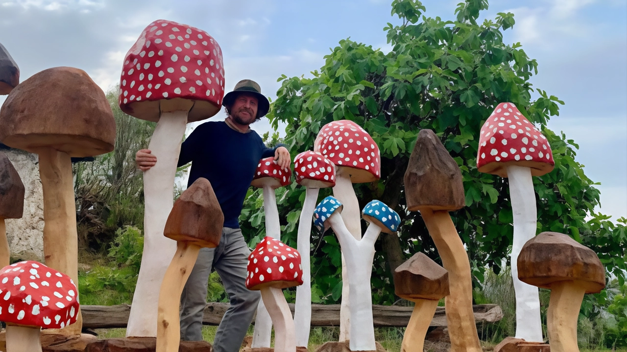 Michel Vecchi, artista italiano noto per le sue allegre e colorate sculture a forma di fungo ricavate da alberi caduti o pericolanti