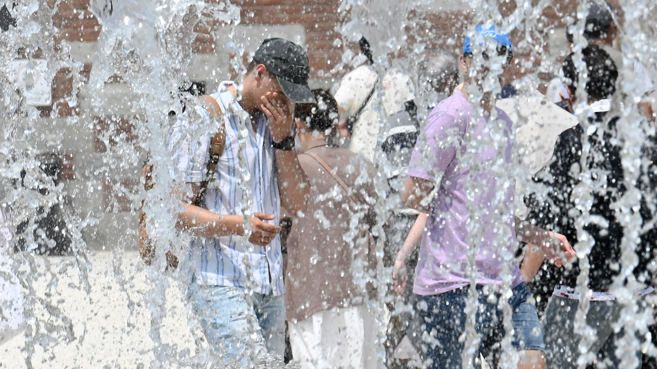 Una persona accaldata cammina accanto alla fontana di piazza Castello a Milano, 13 giugno 2025 (foto Ansa)