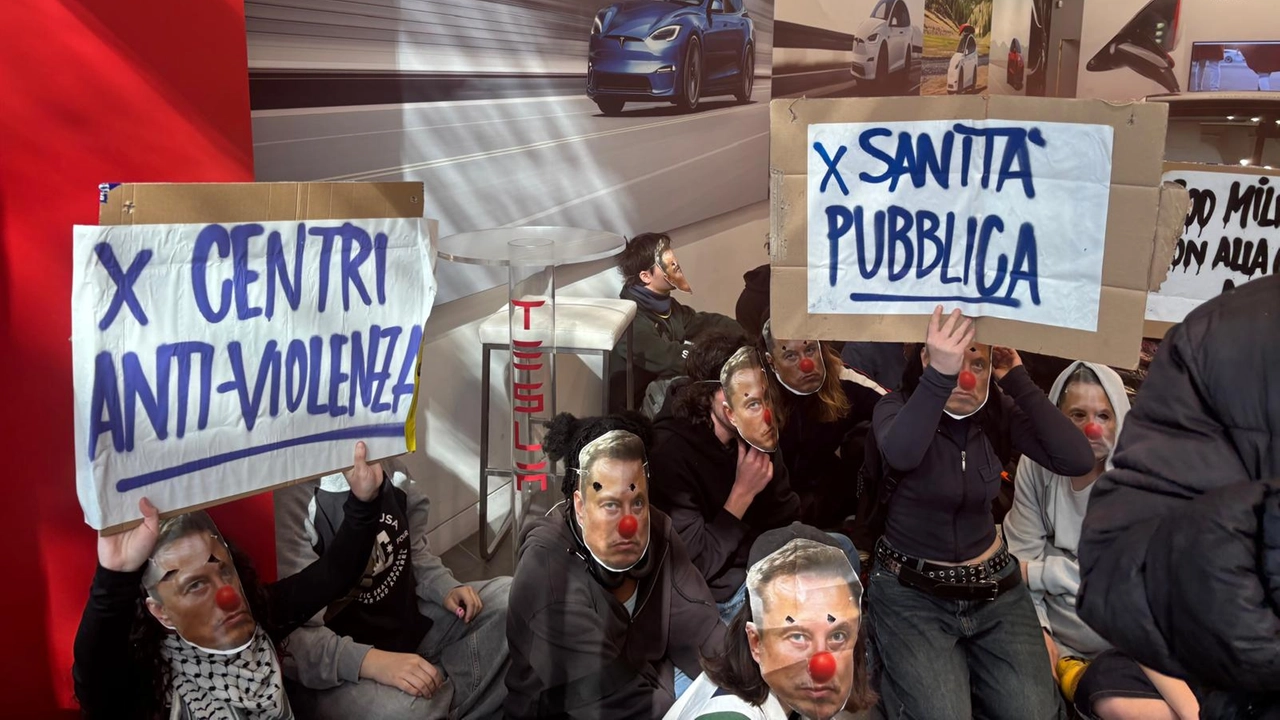 Il gruppo di attivisti che ha effettuato un blitz all'interno di una concessionaria Tesla a Milano (Fasani/Ansa)