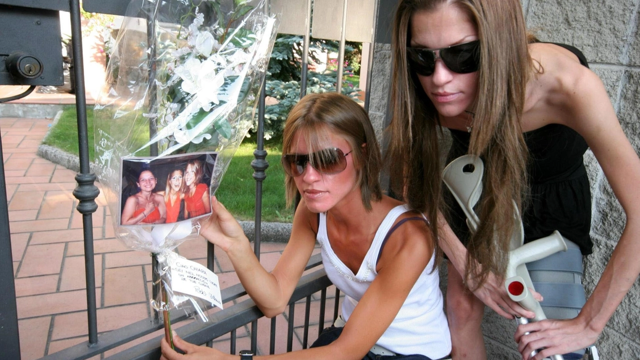 Stefania (a sinistra) e Paola Cappa accanto al mazzo di fiori collocato sul cancello della villetta della famiglia Poggi, con la foto in cui compaiono loro stesse e la cugina