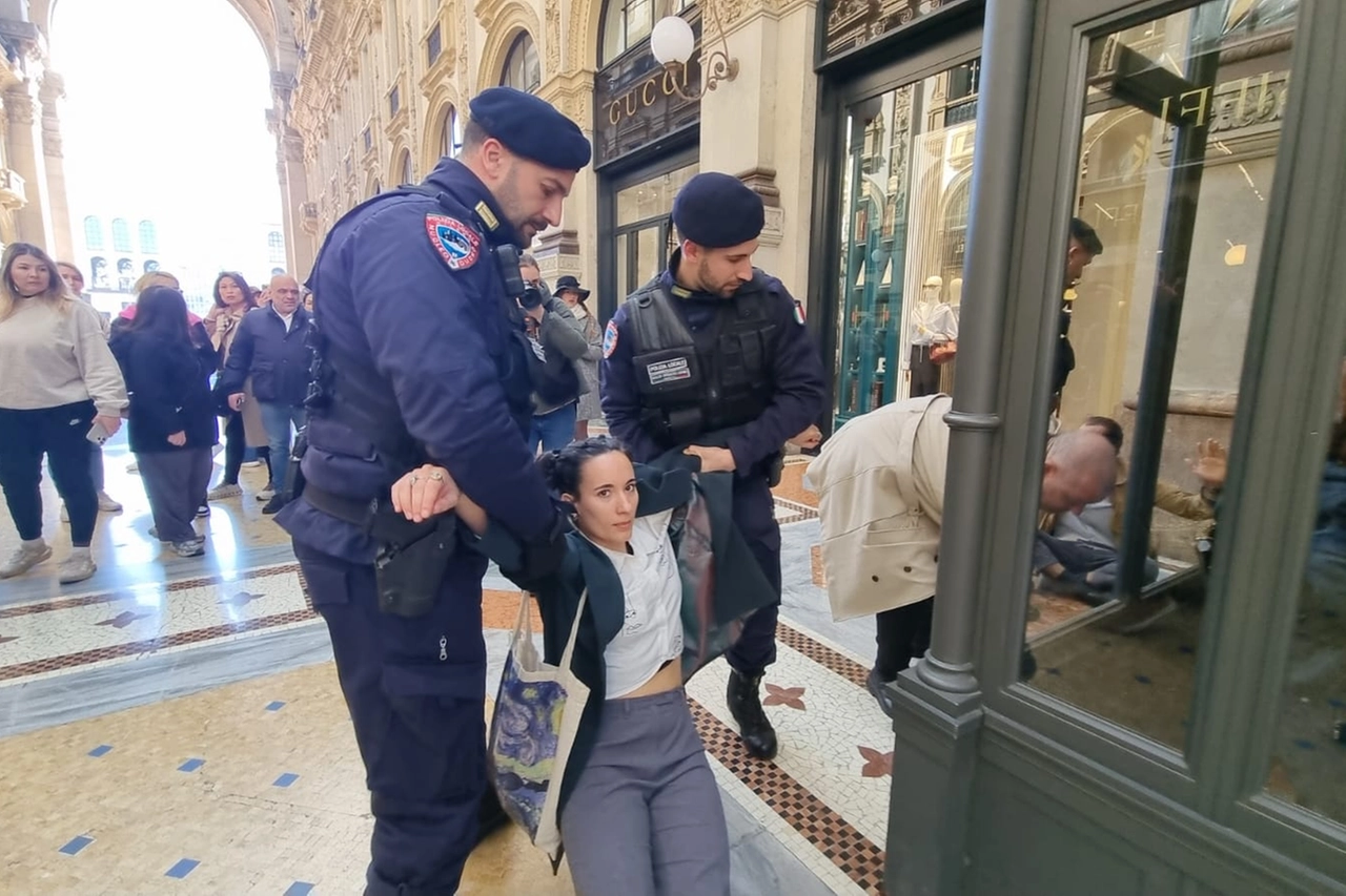 Una delle militanti di Ultima Generazione mentre viene trascinata via dall'esterno del locale in Galleria Vittorio Emanuele II (Fasani)