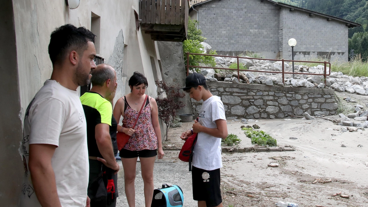 Una famiglia rientra a casa dopo essere stata sfollata a causa delle colate di detriti scatenate dal temporale il 30 giugno