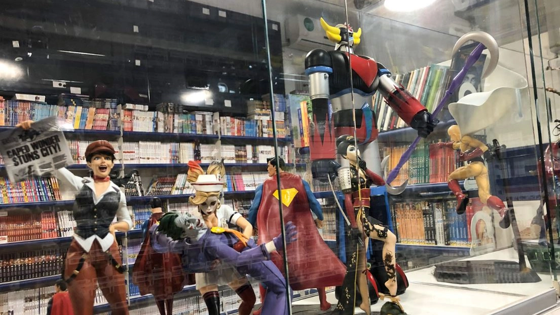 Uno scorcio di “Alastor“ con personaggi in vetrina e sullo sfondo i fumetti (Dal sito giapponemilano.com) Uno scorcio di “Alastor“ con personaggi in vetrina e sullo sfondo i fumetti (Dal sito giapponemilano.com)