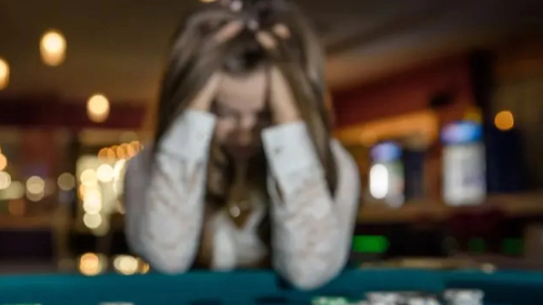Una giocatrice disperata dopo aver perso i soldi nel gioco. Nel 2024 in Lombardia sono stati giocati 25 miliardi tra slot sale giochi e concorsi online