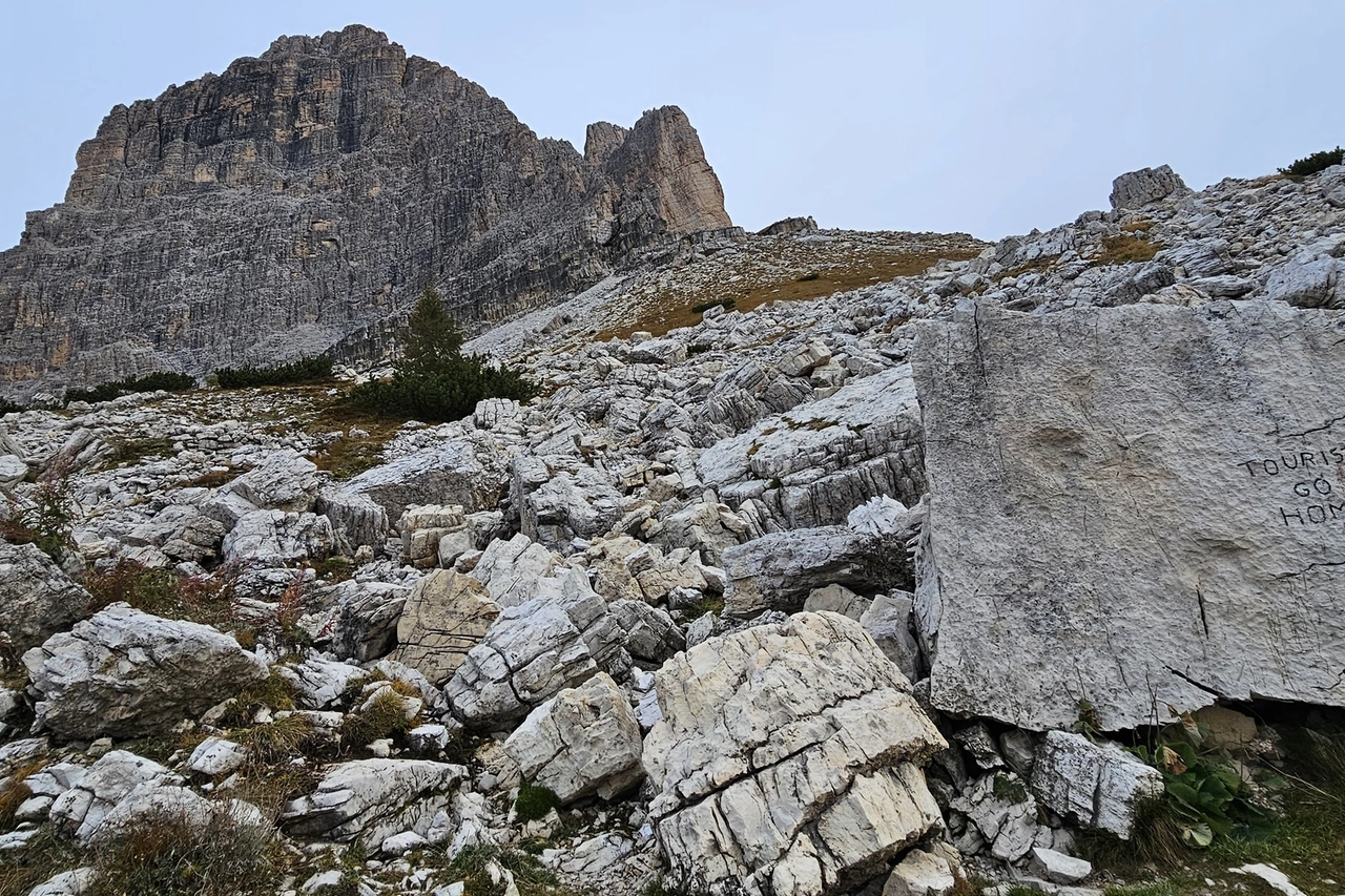 Tre Cime di Lavaredo, scritta "tourists go home" sulla roccia ocn le impronte di dinosauro (foto Moreno Pesce