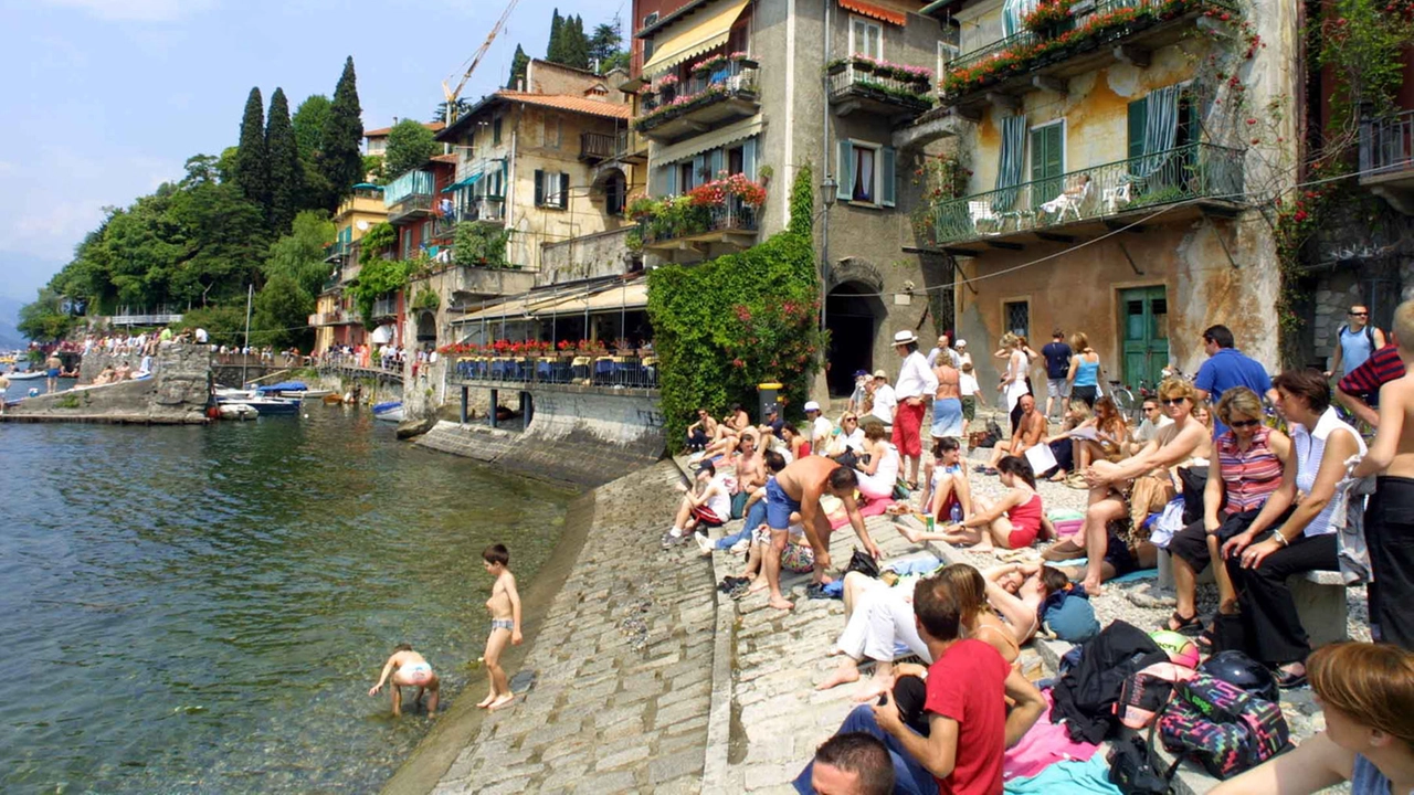 Turisti in spiaggia sul lago a Varenna: presa d’assalto d’estate, spopolata d’inverno