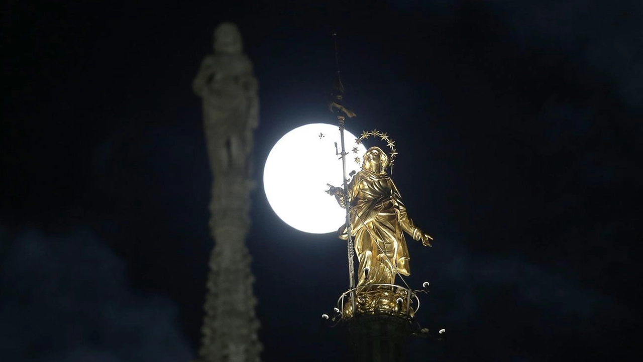 Una luna al perigeo dietro la Madonnina del Duomo di Milano Una luna al perigeo dietro la Madonnina del Duomo di Milano