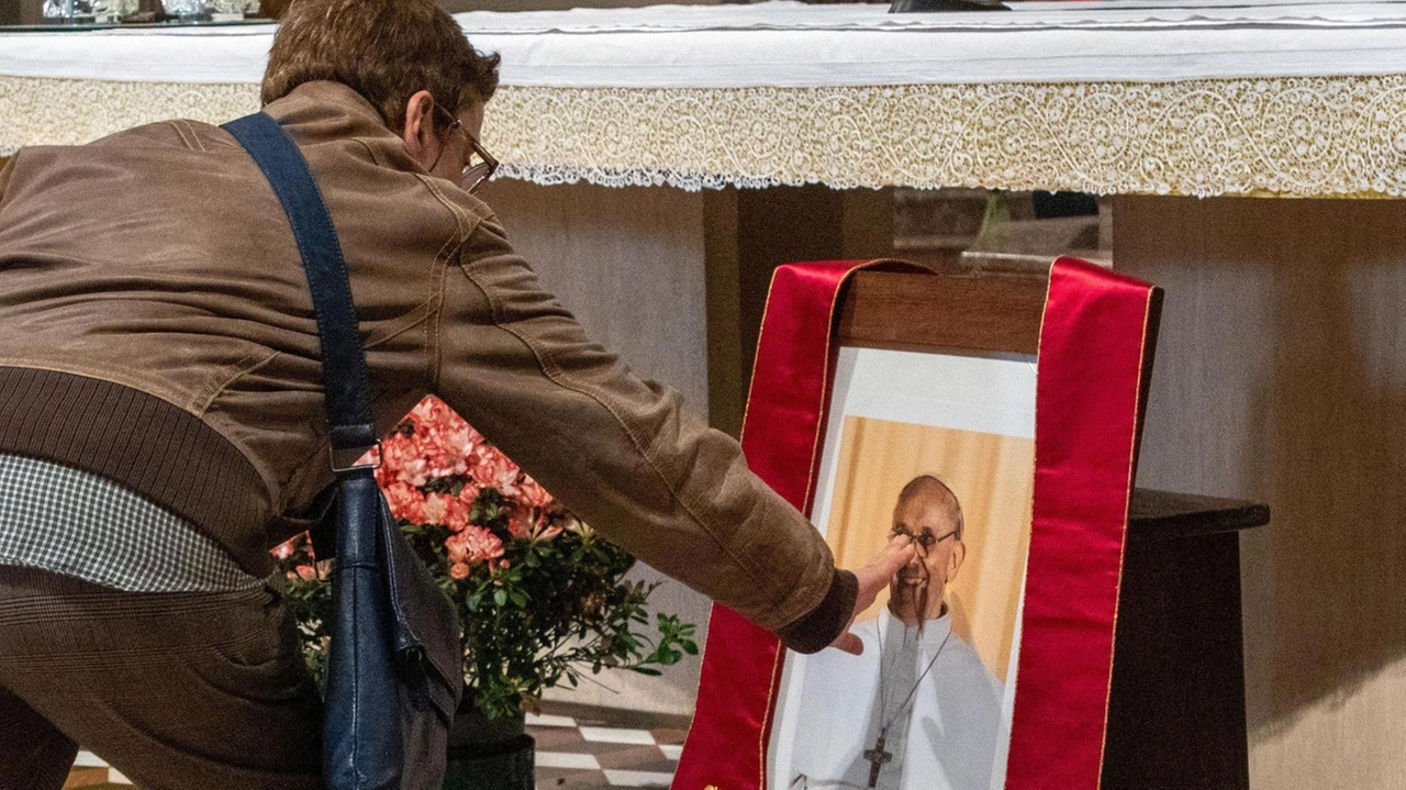 Una fedele tocca la foto di Papa Francesco dopo la cerimonia officiata da monsignor Delpini nella chiesa di Sant’Angelo