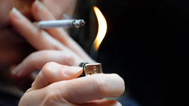 Una donna accende e funa una sigaretta in una foto d'archivio.  ANSA/CLAUDIO ONORATI