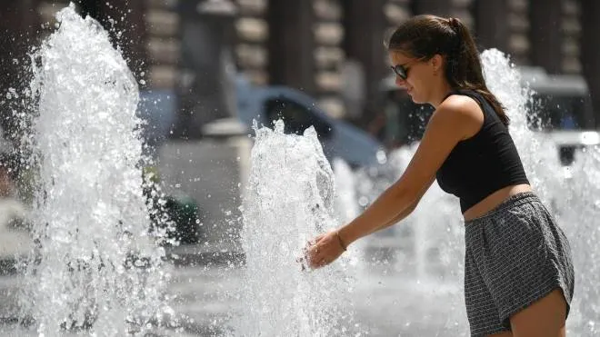 Una turista straniera cerca refrigerio nelle fontane di piazza De Ferrari a Genova, 02 agosto 2018. ANSA/LUCA ZENNARO