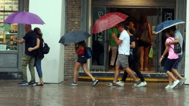 Turisti si riparano dalla pioggia durante il temporale che nel pomeriggio si e' abbattuto sulla città di Bologna, 14 agosto 2018. ANSA/GIORGIO BENVENUTI