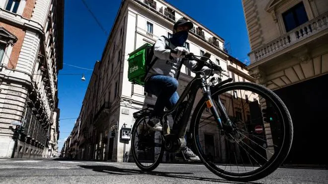 A Uber Eats rider passes on a deserted Via del Corso during the emergency blockade of the Coronavirus Covid-19 in Rome, Italy, 26 April 2020. ANSA/ANGELO CARCONI