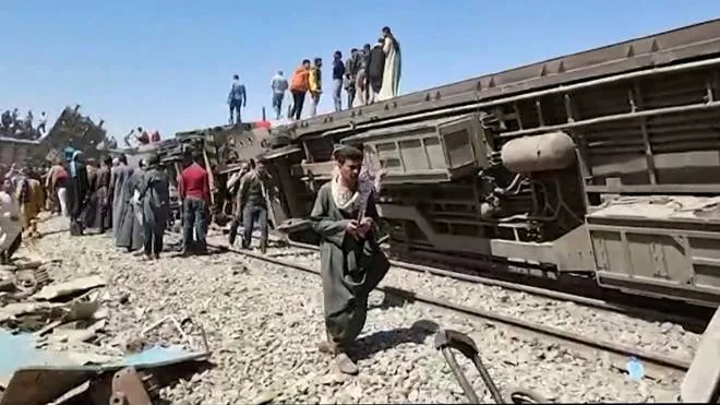 This screengrab provided by AFPTV ahows people gathered around the wreckage of two trains that collided in the Tahta district of Sohag province, some 460 kms (285 miles) south of the Egyptian capital Cairo, reportedly killing at least 32 people and injuring scores of others, on March 26, 2021. - Egypt has been plagued with deadly train accidents in recent years that have been widely blamed on inadequate infrastructure and poor maintenance. (Photo by - / AFP)