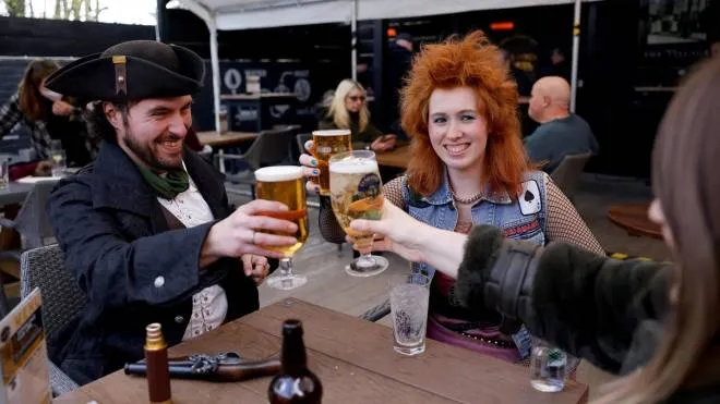 Customers, one dressed as a Pirate, enjoy a drink at the re-opened Village pub in northeast London as coronavirus restrictions are eased across the country in step two of the government's roadmap out of England's third national lockdown on April 12, 2021. - Britons on Monday toasted a significant easing of coronavirus restrictions, with early morning pints -- and much-needed haircuts -- as the country took a tentative step towards the resumption of normal life. Businesses including non-essential retail, gyms, salons and outdoor hospitality were all able to open for the first time in months in the second step of the government's roadmap out of lockdown. (Photo by Tolga Akmen / AFP)
