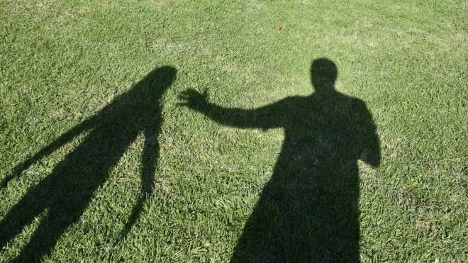 A man's shadow touches the shadow of a girl