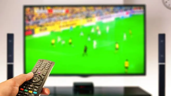 watching soccer at home tv with remote control on hand
