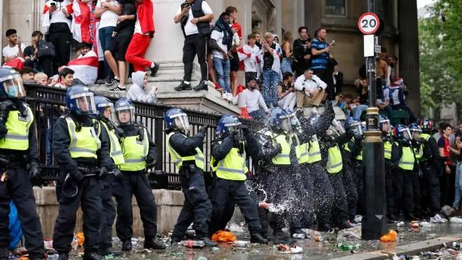 A line of police officers are the target of beer can throwers as England supporters stand around the edges of Trafalgar Square during a live screening of the UEFA EURO 2020 final football match between England and Italy in central London on July 11, 2021. (Photo by Tolga Akmen / AFP)