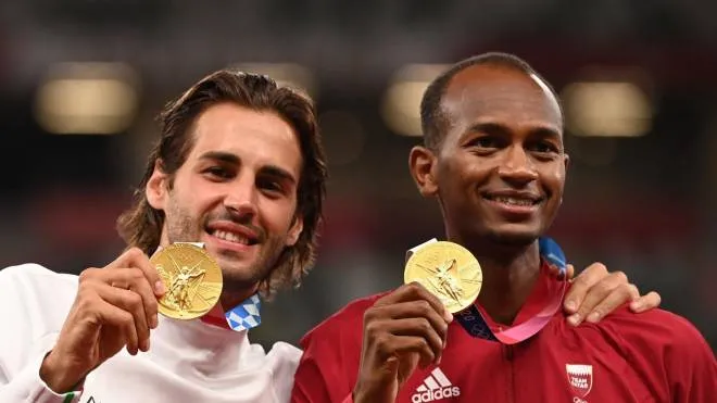 Joint gold medalists Qatar's Mutaz Essa Barshim (R) and Italy's Gianmarco Tamberi pose on the podiumn of the men's high jump final during the Tokyo 2020 Olympic Games at the Olympic Stadium in Tokyo on August 2, 2021. (Photo by Ina FASSBENDER / AFP)