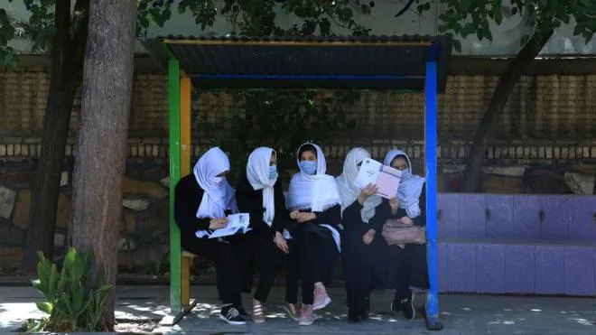Schoolgirls sit at the schoolyard in Herat on August 17, 2021, following the Taliban stunning takeover of the country. (Photo by AREF KARIMI / AFP)