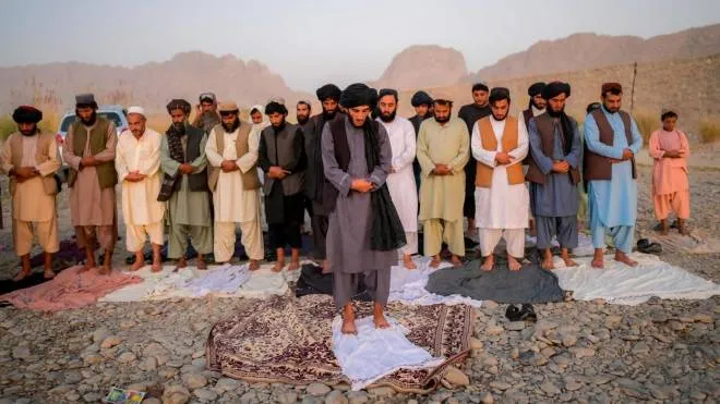TOPSHOT - In this picture taken on September 23, 2021, Taliban members pray on the banks of a river in Kandahar. (Photo by Bulent KILIC / AFP)