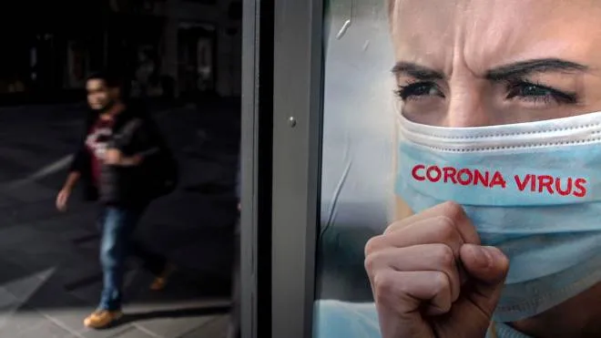 A man passes by an advertisement with the slogan 'Corona Virus' on it in Vienna, Austria, 16 March 2020. ANSA/CHRISTIAN BRUNA