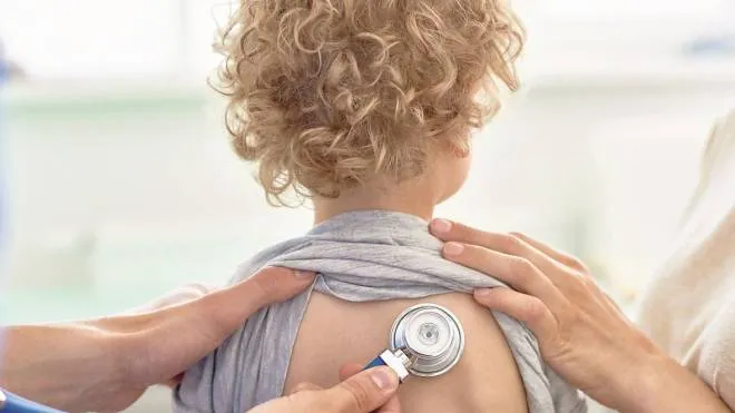 Unrecognizable male pediatrician examining curly little patient with help of stethoscope, blurred background PEDIATRA