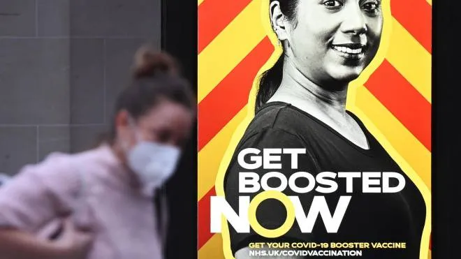 epa09643392 A shopper walks past a government Covid-19 booster campaign advertisement in London, Britain, 15 December 2021. The UK government has warned the public that the country is facing a 'tidal wave' of Omicron infections with currently sixty thousand infections a day. The UK Covid-19 booster rollout is aiming to jab some one million people a day to fight an Omicron wave.  EPA/ANDY RAIN