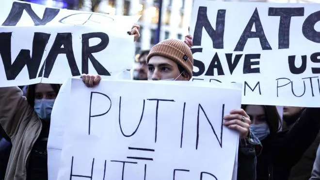 A protester holds a placard during a rally against Russia's military operation in Ukraine, in front of the russian mission in Brussels on February 24, 2022. - Russian President Vladimir Putin launched a full-scale invasion of Ukraine on February 24, killing dozens and forcing hundreds to flee for their lives in the pro-Western neighbour. Russian air strikes hit military facilities across the country and ground forces moved in from the north, south and east, triggering condemnation from Western leaders and warnings of massive sanctions. (Photo by Kenzo TRIBOUILLARD / AFP)