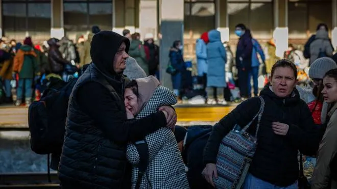 A man hugs his wife before she boards an evacuation train at Kyiv central train station on February 28, 2022. - The Russian army said on February 28 that Ukrainian civilians could "freely" leave the country's capital Kyiv and claimed its airforce dominated Ukraine's skies as its invasion entered a fifth day. (Photo by Dimitar DILKOFF / AFP)
