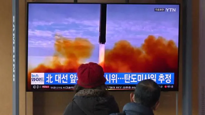 People watch a television screen showing a news broadcast with file footage of a North Korean missile test, at a railway station in Seoul on March 5, 2022, after North Korea fired at least one "unidentified projectile" in the country's ninth suspected weapons test this year according to the South's military. (Photo by Jung Yeon-je / AFP)