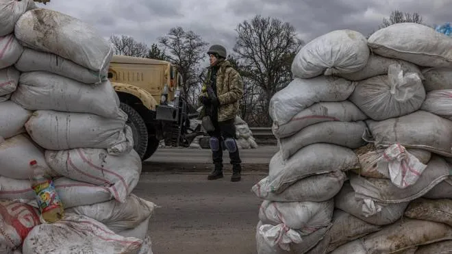 Un soldato ucraino pattuglia un check point in ingresso a Kiev