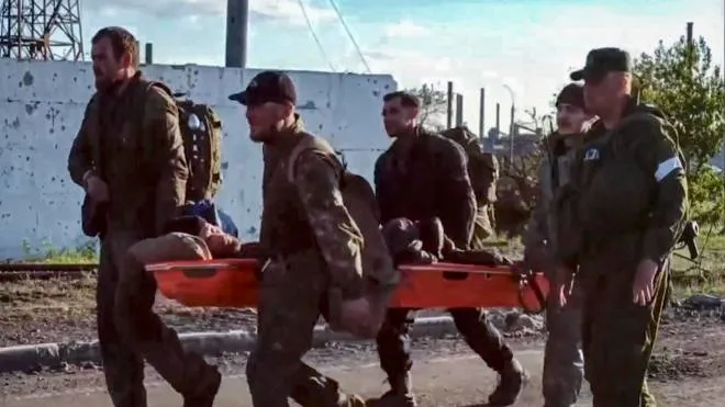 A handout still image taken from a handout video made available by the Russian Defence Ministry's press service shows Ukrainian servicemen carry a wounded comrade on a stretcher as they are being evacuated from the besieged Azovstal steel plant in Mariupol, Ukraine, 17 May 2022. A total of 265 Ukrainian militants, including 51 seriously wounded, have laid down arms and surrendered to Russian forces, the Russian Ministry of Defence said on 17 May 2022. Those in need of medical assistance were sent for treatment to a hospital in Novoazovsk, the ministry states further. Russian President Putin on 21 April 2022 ordered his Defence Minister to not storm but to blockade the plant where a number of Ukrainian fighters were holding out. On 24 February, Russian troops invaded Ukrainian territory starting a conflict that has provoked destruction and a humanitarian crisis. According to the UNHCR, more than six million refugees have fled Ukraine, and a further 7.7 million people have been displaced internally within Ukraine since.  ANSA/RUSSIAN DEFENCE MINISTRY PRESS SERVICE HANDOUT  BEST QUALITY AVAILABLE HANDOUT EDITORIAL USE ONLY/NO SALES