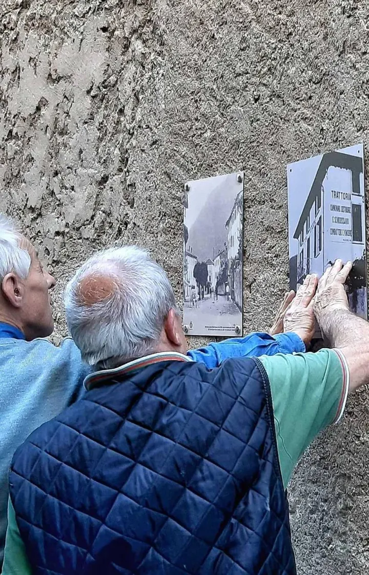 Un paio di visitatori in una via di Dervio mentre ammirano le vecchie immagini