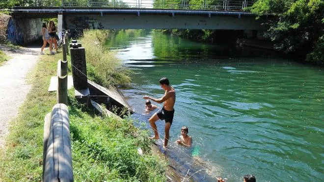 Alcuni ragazzi cercano riparo dal caldo tuffandosi nelle acque del Villoresi