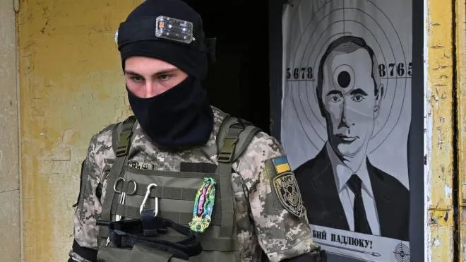 A fighter of the territorial defence unit, a support force to the regular Ukrainian army, leaves an abandoned building with a target on its door depicting Russian President Vladimir Putin, as he takes part with others in a training exercise outside Kyiv on May 20, 2022. - Russian soldiers are now focused on the south and eastern regions of Ukraine, but -- anticipating a drawn-out conflict -- Kyiv has stepped up the training of its new recruits so they are ready to face the enemy if and when needed. (Photo by Sergei SUPINSKY / AFP)