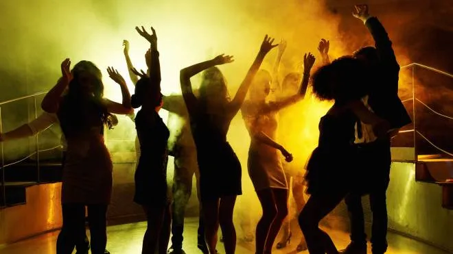Silhouettes of group of people grooving on the dance floor at a night club