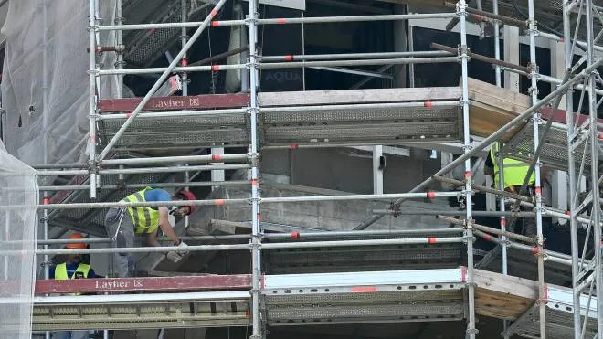 Operai edili al lavoro sulla facciata di  un palazzo ricoperto da ponteggi, Milano, 14 giugno 2022. ANSA/DANIEL DAL ZENNARO