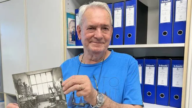 Lino Forti mostra una foto della sua officina nel 1962