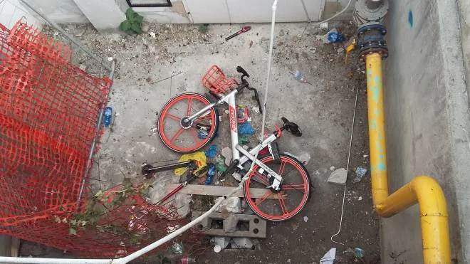 La bicicletta grigio-arancione della free floating e il monopattino gettati nel seminterrato del Capannone Sud insieme ad altra spazzatura