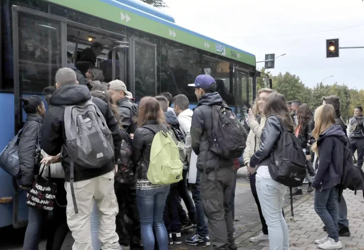 Un gruppo di studenti tenta invano di salire su un autobus già strapieno
