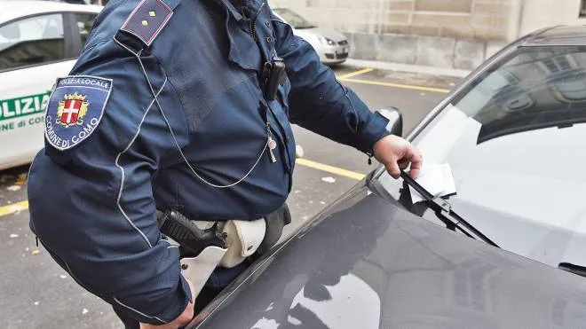 Un agente della polizia locale di Como mentre posiziona un verbale