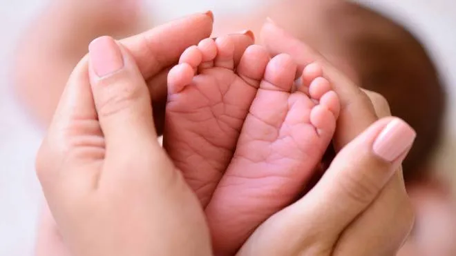 piedi neonato Mother holding tiny foot of newborn baby iStockphoto