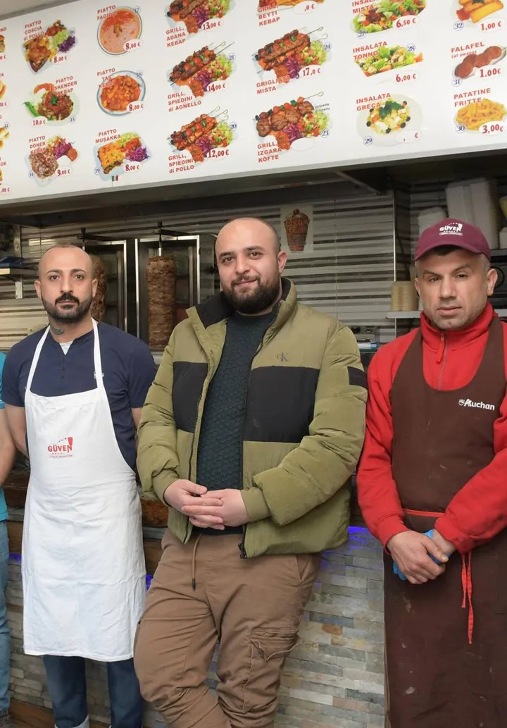 Huseyin Idiris, al centro, è in Italia da 17 anni e gestisce una pizzeria-kebab che ora è. centro di raccolta degli aiuti