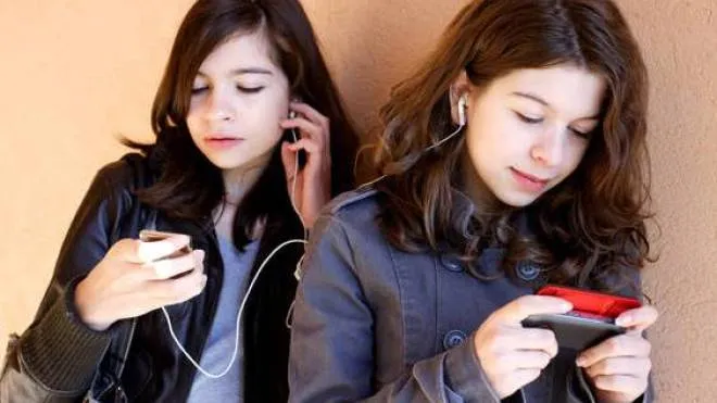 Two teenager girls listening to music on MP3 player.