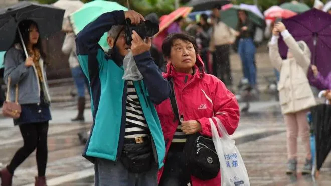 Turisti visitano il centro della città indossando giacche e proteggendosi dalla pioggia con ombrelli a causa del maltempo,29 ottobre 2018.ANSA/DANIEL DAL ZENNARO